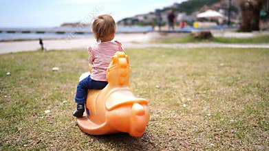 Little girl climbs on a swing-balancer crouching