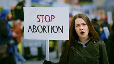 Woman hold abortion prohibition banner at pro life protest. Anti baby murder.