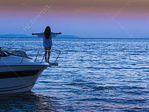 Attractive woman at boat on sea at sunset