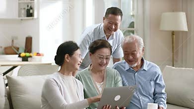 two asian couples looking at laptop computer together