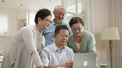 two senior asian couples laptop computer together at home