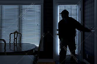 Burglar Breaking In To Home At Night Through Back