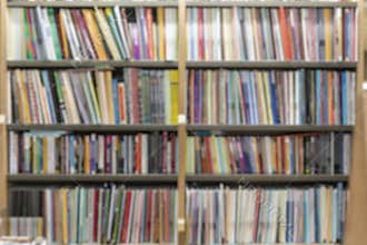 Bookshelves filled with variety of colorful books in library. Image is blurred creating soft focus on collection of