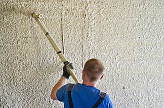 Man spraying concrete stucco to wall