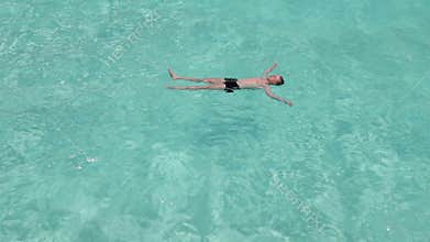 Teenager has a rest on turquoise transparent water of ocean
