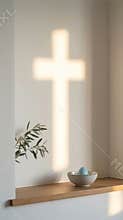 Shadow of cross falls on wall in bright interior. Bowl with blue egg sits on wooden shelf alongside green plant. Concept