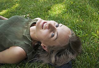 Happy woman laying on grass smiling