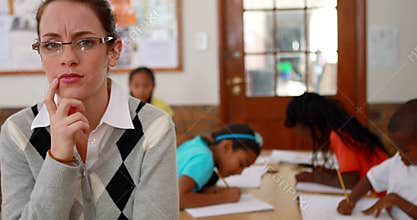 Thoughtful teacher looking at camera at top of classroom