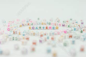 Letters scatter across a surface with one word highlighted in the center on a light background during a creative activity