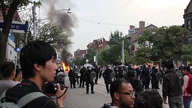 Riot officers forming line with fire