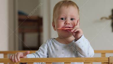White baby teething in wooden crib