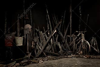 A somber scene of charred wreckage, burnt beams, and rusted objects