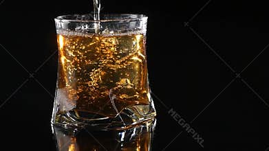 Whiskey being poured into a glass against black