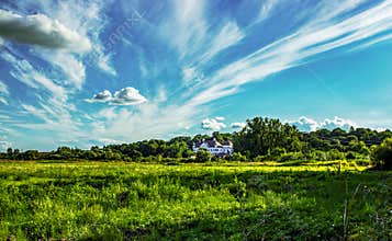 Historic countryside mansion under dramatic blue sky