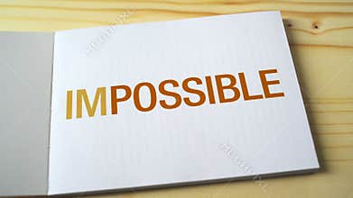 Impossible becomes possible by fading letters printed on the notebook page.