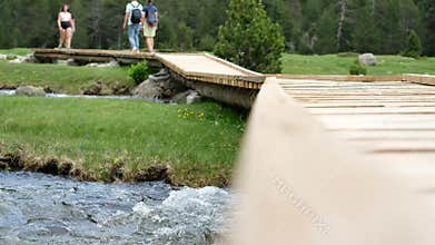 Blurred View of Tourists are Passing through Winding Wooden Bridge-trail.