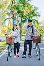 A friend couple are walking and chatting with bicy