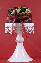 Festive Christmas food, fruit cake with glace cherries and nuts on white cake against a red background