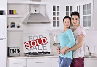 Happy Couple in Front of Sold Real Estate Sign