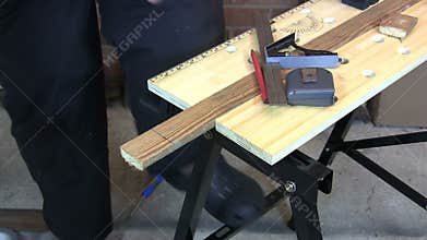 Man drawing a line and cutting a piece of wood with a saw