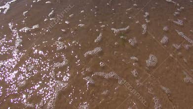 Sea waves removing footprints from beach sand