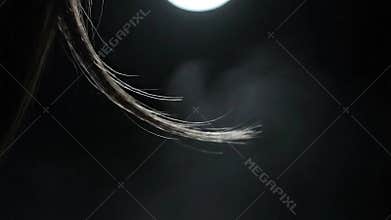 Close Up of Delicate Hair Strands Catching Light Under a Dim Spotlight Against a Dark Moody Background
