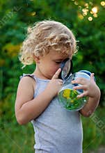 A child looks into a jar with a magnifying glass. Selective focus.