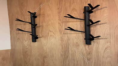 Two modern black coat racks adorn a light wooden wall. These stylish
