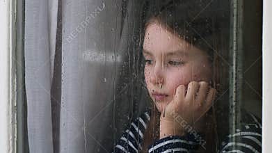 Portrait Caucasian little girl child kid looking out window rainy weather suffering with lonely look at rain orphan