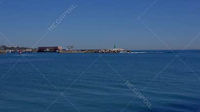 Green beacon standing on concrete blocks protecting harbor entrance from waves - MARBELLA, SPAIN - MARCH 30, 2025
