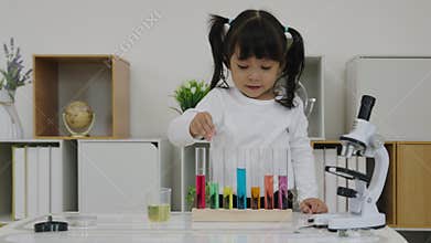 toddler girl scientist study using pipette dropping liquid with test tube and beaker