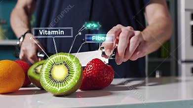 sliced orange and kiwi on counter, hands slice fruit with chef knife while digital labels highlight vitamin and fiber