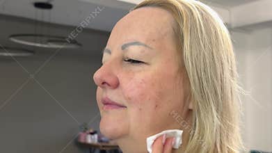 Beauty salon skin care master applies to woman micellar water tonic to moisturize and cleanse the skin youth anti-aging