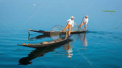 Two fishermen on traditional boats turning. Inle Lake, Myanmar