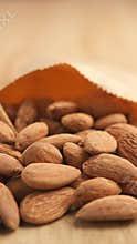 Almonds scattered from a paper bag on a wooden table
