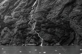 A stream trickles down the stone face of a mountain in the Endicott Fjord in Alaska