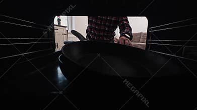 Man Placing Frying Pans Into Oven