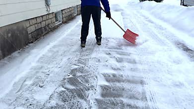 Shoveling snow with an orange shovel