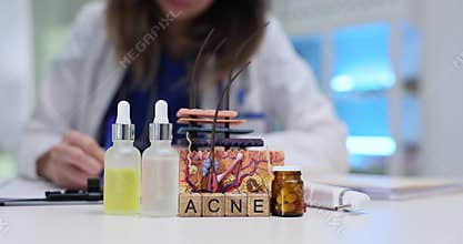 Wooden blocks spell word Acne near serum bottles and skin model