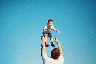 Happy joyful child, father fun throws up son in the air, summer