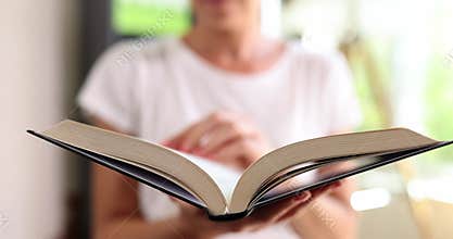 Female reader flips pages studying chapter in open thick book