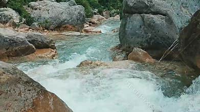 Fast moving turquoise stream rushing over smooth rocks with rapids and small waterfalls