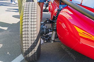 Close-up of a retro Formula 1 car, focusing on the red right front tire with black accents and sponsor logos Detailed tread