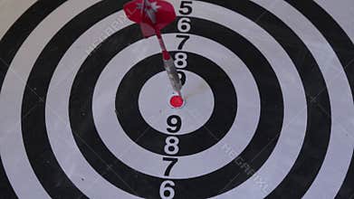 A close-up shot of a dart hitting the bullseye on a black and white target, symbolizing success and goal achievement.