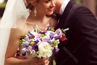 Beautiful bridal couple having fun in the park on their wedding day flower bouquet