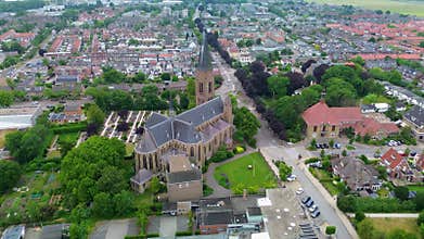 Aerial view of a grand historic church or cathedral with a tall green patina tower, arched windows, and stone detailing, set among