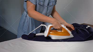 Unrecognizable woman ironing a man's shirt at home. Domestic life chore.