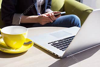 Using mobile phone and laptop computer in cafe