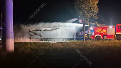 Semi-trailer with batteries on fire and being extinguished by firefighters.