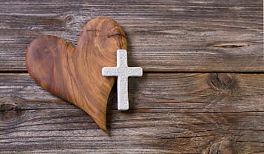 Wooden background with olive heart and white cross for an obituary notice.